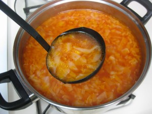scooping cabbage soup out of pot with a ladle