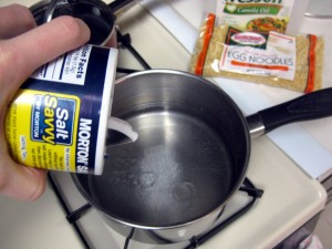 pouring salt into pot for making pasta