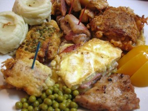 huge plate of cheese ham and egg loaded schnitzels with baked and mashed potoates apricots and peas