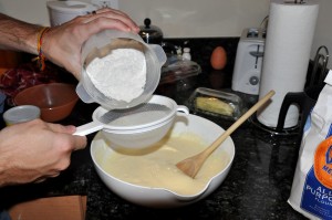adding flour to egg mixture through a strainer